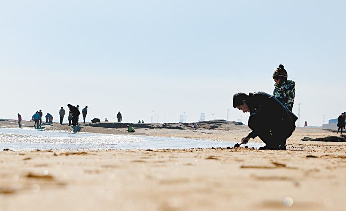 2月24日,游客在灯塔风景区附近的海滩游玩.